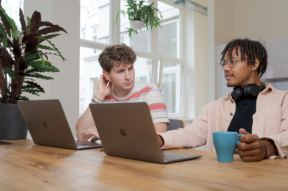 Two males sat a table on their Macbooks using the best ecommerce accounting software