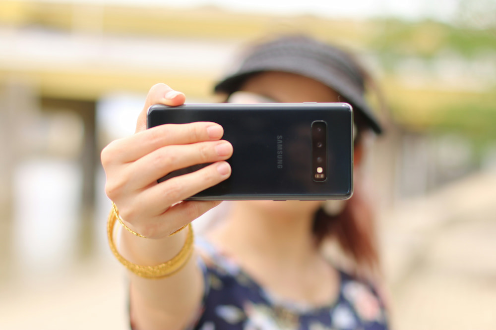 Influencer girl taking a selfie on her phone. The mobile phone is in front of her face.